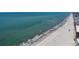 Aerial view of a long sandy beach with waves crashing onto the shore, and a city in the background at 460 137Th Avenue Cir, Madeira Beach, FL 33708