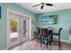 Dining area featuring aqua-colored walls, a ceiling fan, wood-look flooring, and access to outdoor patio at 460 137Th Avenue Cir, Madeira Beach, FL 33708
