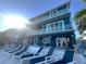 Expansive waterfront home with multiple balconies, a row of lounge chairs, and a sun-drenched patio at 460 137Th Avenue Cir, Madeira Beach, FL 33708