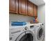Well-lit laundry room featuring wooden cabinets above a modern, front-loading washer and dryer at 5353 Gulf Blvd # B103, St Pete Beach, FL 33706