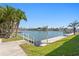 Serene waterfront view from a meticulously maintained lawn with docks and palm trees on the horizon at 5353 Gulf Blvd # B103, St Pete Beach, FL 33706