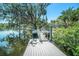 Backyard view from dock, showing mature landscaping, pool, and house at 5910 River Rd, New Port Richey, FL 34652