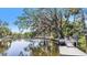 View of canal with pier and dock, along with lush landscaping and other houses at 5910 River Rd, New Port Richey, FL 34652