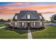 Charming two-story home featuring a columned front porch and lush green lawn with a beautiful sunset sky at 6518 Paw Pl, Land O Lakes, FL 34639