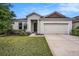 Charming single-story home featuring a well-manicured lawn, neutral paint, and an attached two-car garage at 672 Old Windsor Way, Spring Hill, FL 34609