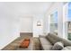 Minimalist living room featuring neutral tones, wood-look tile flooring, and natural light from a large window at 672 Old Windsor Way, Spring Hill, FL 34609
