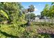 Secluded backyard featuring lush vegetation, palm trees and a storage shed with a white fence at 6907 W Creek Dr, Tampa, FL 33615