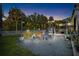 Backyard at dusk with a firepit surrounded by string lights, white fence, and green trees at 6907 W Creek Dr, Tampa, FL 33615