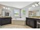 Bathroom featuring a corner tub, dual sinks with granite countertops, and large mirrors at 8227 Bird Whistle Ln, Land O Lakes, FL 34637