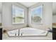 Close up view of corner bathtub, showing tile surround and natural light from the window at 8227 Bird Whistle Ln, Land O Lakes, FL 34637