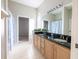 A well-lit bathroom featuring a double sink vanity with granite countertops and decorative plants at 9159 Highland Ridge Way, Tampa, FL 33647