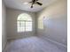 Spacious bedroom featuring neutral carpet, a large arched window and ceiling fan at 9159 Highland Ridge Way, Tampa, FL 33647