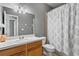 Cozy bathroom featuring a toilet, sink, mirror and patterned shower curtain at 13312 Tiger Lilly Ln, Tampa, FL 33625
