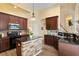Elegant kitchen featuring dark wood cabinetry, black countertops and a central island with a stone base at 13312 Tiger Lilly Ln, Tampa, FL 33625