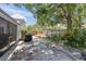 Private backyard oasis with a stone patio area, mature trees, and lush landscaping around a wooden fence at 1428 Chesterfield Dr, Dunedin, FL 34698