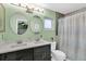 A bathroom with double sinks, marble countertops, dual circular mirrors, and a walk-in shower at 1428 Chesterfield Dr, Dunedin, FL 34698