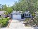 Charming single-story home featuring a two-car garage, mature shade tree, and manicured landscaping at 1428 Chesterfield Dr, Dunedin, FL 34698