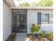 Home's front entrance with screened-in porch, dark door with wreath, and small garden at 1428 Chesterfield Dr, Dunedin, FL 34698