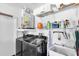 Well-equipped laundry room with modern washer and dryer, storage shelving, and utility sink at 1428 Chesterfield Dr, Dunedin, FL 34698