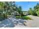 Property featuring circular driveway, mature trees, and single story home with red door at 1603 Cottagewood Dr, Brandon, FL 33510