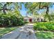 Inviting home with red door, shutters, and lush landscaping along long driveway at 1603 Cottagewood Dr, Brandon, FL 33510
