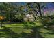 Lush front lawn and mature trees surround this charming home with a red door at 1603 Cottagewood Dr, Brandon, FL 33510