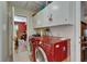 Practical laundry area with modern red washer and dryer and overhead cabinets for storage at 1603 Cottagewood Dr, Brandon, FL 33510