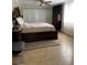 This is a bedroom with tan-colored tile floors, a wooden bed frame, and white closet doors at 1748 Ragland Ave, Clearwater, FL 33765