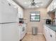 Well-lit kitchen with white appliances, bright white cabinetry, and a window at 2700 Cove Cay Dr # 1-2D, Clearwater, FL 33760