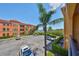 Balcony view overlooking manicured landscaping and complex parking with a beautiful blue sky above at 2739 Via Capri # 1024, Clearwater, FL 33764