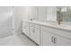 Modern bathroom featuring dual sinks, white cabinetry, quartz countertops, and marble tile flooring at 28776 Rambutan Dr, Wesley Chapel, FL 33543