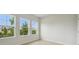 Bright bedroom with three large windows overlooking lush greenery and hardwood flooring at 28776 Rambutan Dr, Wesley Chapel, FL 33543