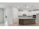 Open kitchen with large island, white cabinets, modern appliances, and light hardwood flooring at 28776 Rambutan Dr, Wesley Chapel, FL 33543