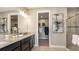 Modern bathroom featuring double sinks, granite countertops, a walk-in closet, and a glass-enclosed shower at 29516 Zupetta Ln, Wesley Chapel, FL 33545
