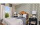 Cozy bedroom with patterned wallpaper, white bedding, side tables with lamps and a view from the arched window at 29516 Zupetta Ln, Wesley Chapel, FL 33545