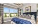 Serene main bedroom with large windows, chandelier, tray ceiling, plush bedding, and calming blue accents and artwork at 29516 Zupetta Ln, Wesley Chapel, FL 33545