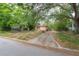 View of a quaint home with a long driveway surrounded by mature trees and lush greenery at 3027 W Helen Ave, Tampa, FL 33611