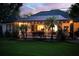 Backyard at dusk featuring a screened pool, tropical landscaping, and ambient outdoor lighting at 3329 Cypress Landing Dr, Valrico, FL 33596