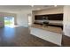 Open-concept kitchen features granite countertops, stainless appliances, and an island overlooking the living area at 35003 Daisy Meadow Loop, Zephyrhills, FL 33541