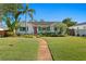 Charming home featuring a well-manicured lawn, mature palms, and a welcoming walkway to the front door at 432 39Th Ne Ave, St Petersburg, FL 33703