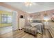 Cozy bedroom with a queen-sized bed, wood floors, pink walls, and a glimpse into another room at 5247 81St N St # 4, St Petersburg, FL 33709