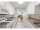 Narrow galley kitchen with white cabinets and appliances overlooking the living room, ample countertop space, and tile flooring at 5247 81St N St # 4, St Petersburg, FL 33709