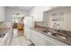 Cozy kitchen features white cabinets and appliances and a stainless steel sink with a view to the living room at 5247 81St N St # 4, St Petersburg, FL 33709