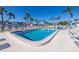 Community pool surrounded by palm trees, lounge chairs, and a secure fence at 5247 81St N St # 4, St Petersburg, FL 33709