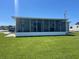 Rear view of home with a screened-in porch and expansive green lawn at 57 Harbor Way # 24, Palm Harbor, FL 34684