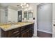 Bathroom featuring double sinks with granite countertop and dark wood cabinets and a white door to the left at 6006 Chellas Ct, Lutz, FL 33558