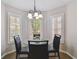 Bright dining area with a glass table, black chairs, and a modern chandelier beneath three large windows at 6006 Chellas Ct, Lutz, FL 33558
