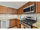 Close-up of kitchen with stainless steel appliances, granite countertops, and wood cabinets at 6006 Chellas Ct, Lutz, FL 33558