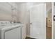 Laundry area with a washing machine, dryer, shelving, and a door at 6006 Chellas Ct, Lutz, FL 33558