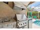 This outdoor kitchen features a built-in grill, sink, vent hood, and mini-fridge, perfect for entertaining by the pool at 6006 Chellas Ct, Lutz, FL 33558